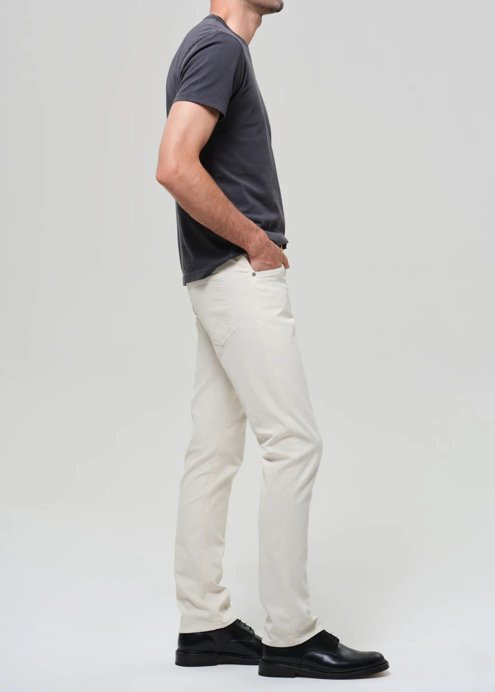Person wearing a dark gray t-shirt and white pants on a light gray background