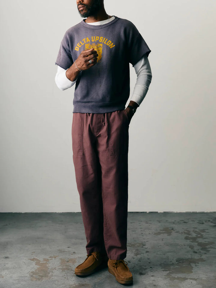 Person wearing a gray sweatshirt with 'Delta Upsilon' text and maroon pants against a plain background