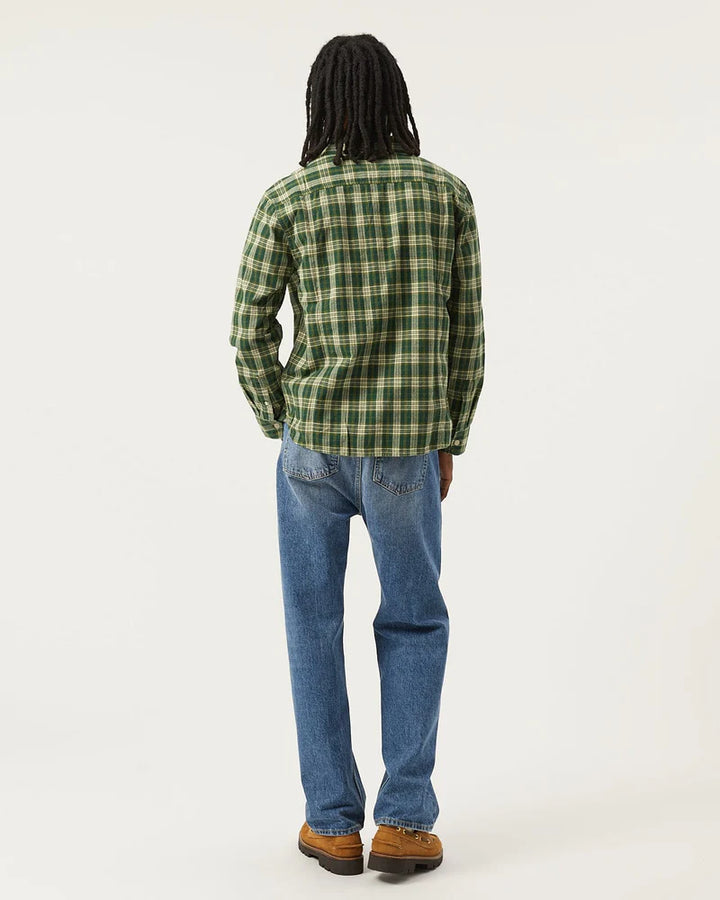 Person wearing a green plaid shirt and blue jeans on a white background