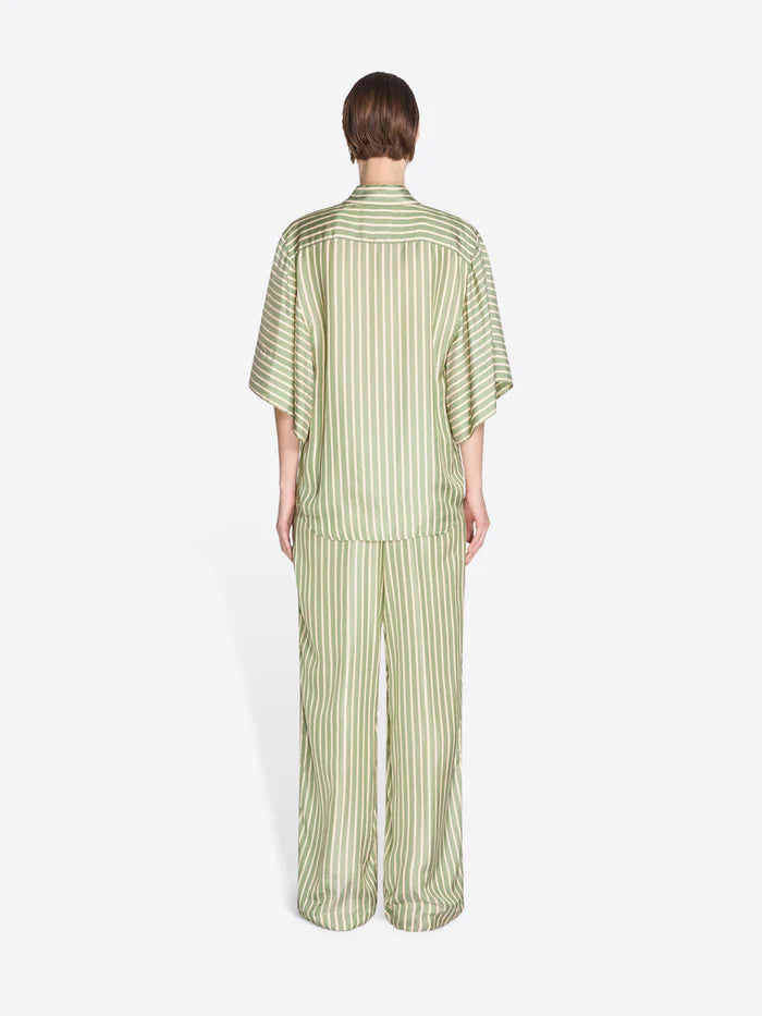 Person wearing a green striped pajama set on a white background