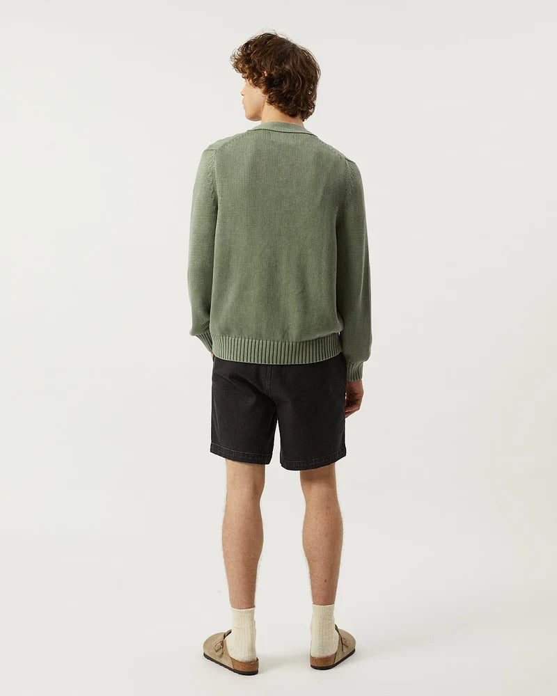 Person wearing a green sweater and black shorts on a white background