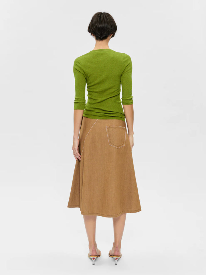 Person wearing a green top and brown skirt on a white background