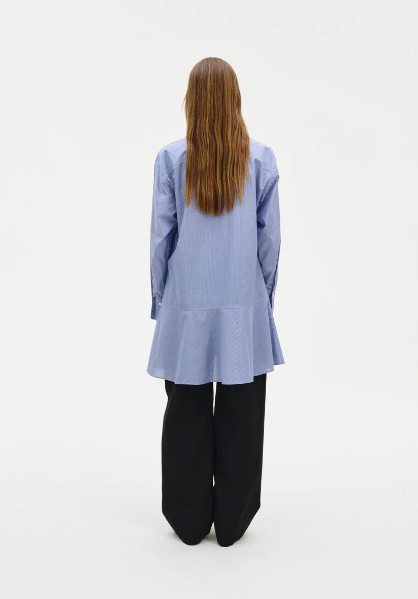 Person wearing a light blue jacket and black pants on a white background