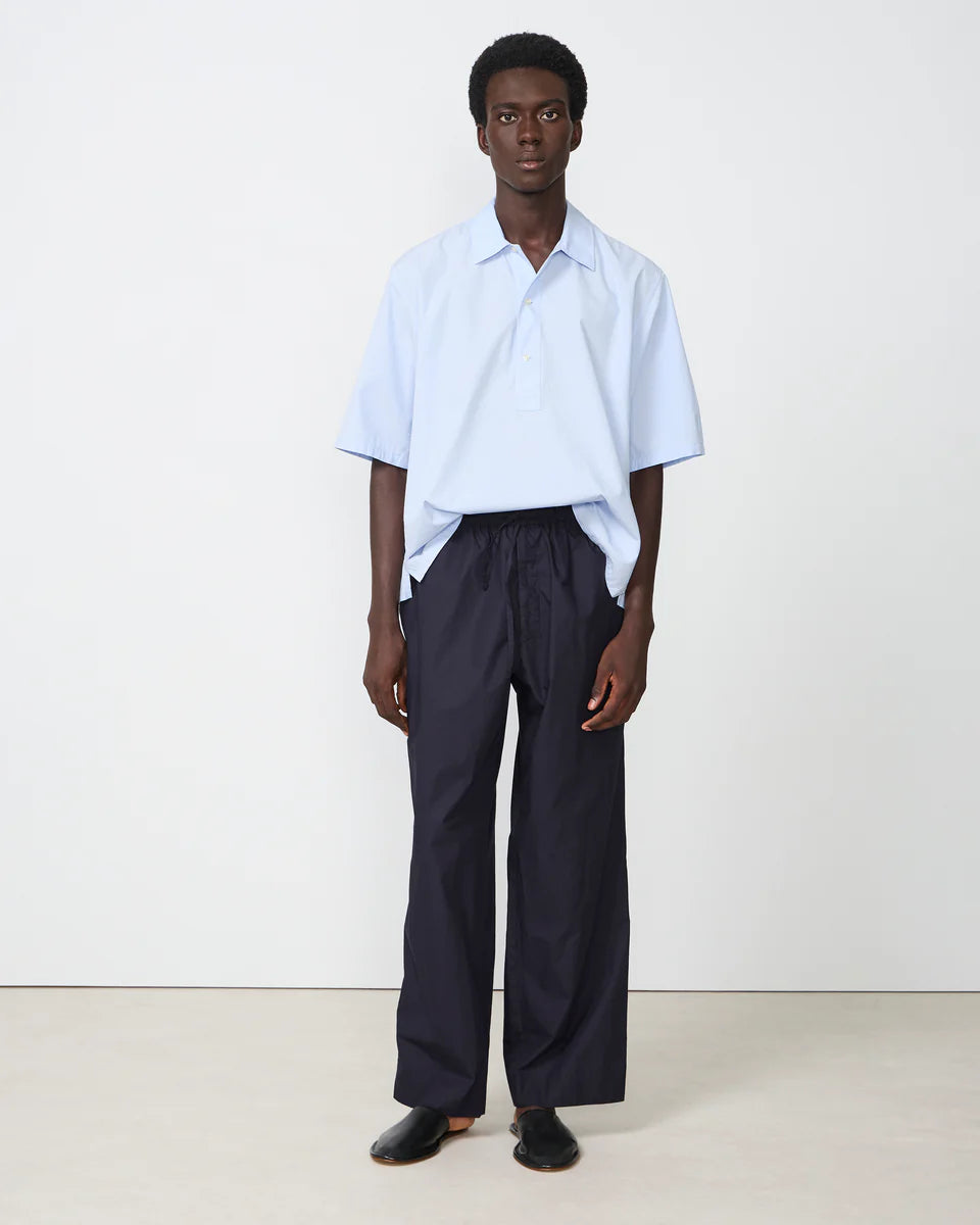 Person wearing a light blue shirt and dark pants on a white background