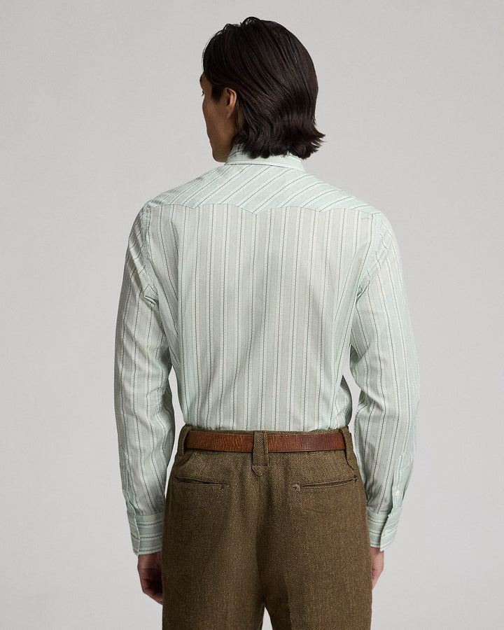 Person wearing a light green striped shirt and brown pants on a gray background