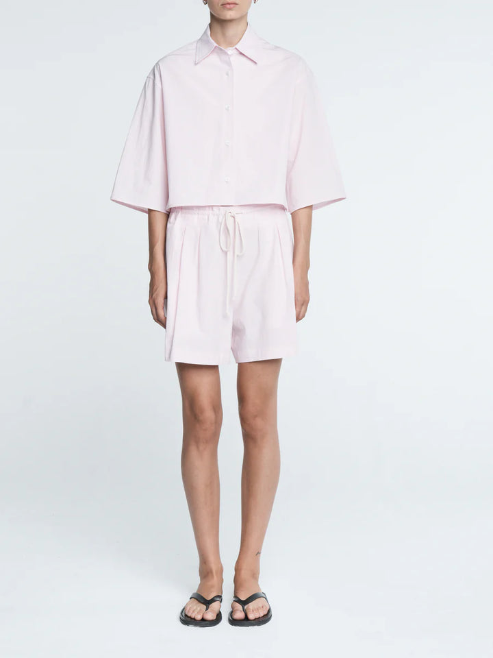 Person wearing a light pink outfit on a white background