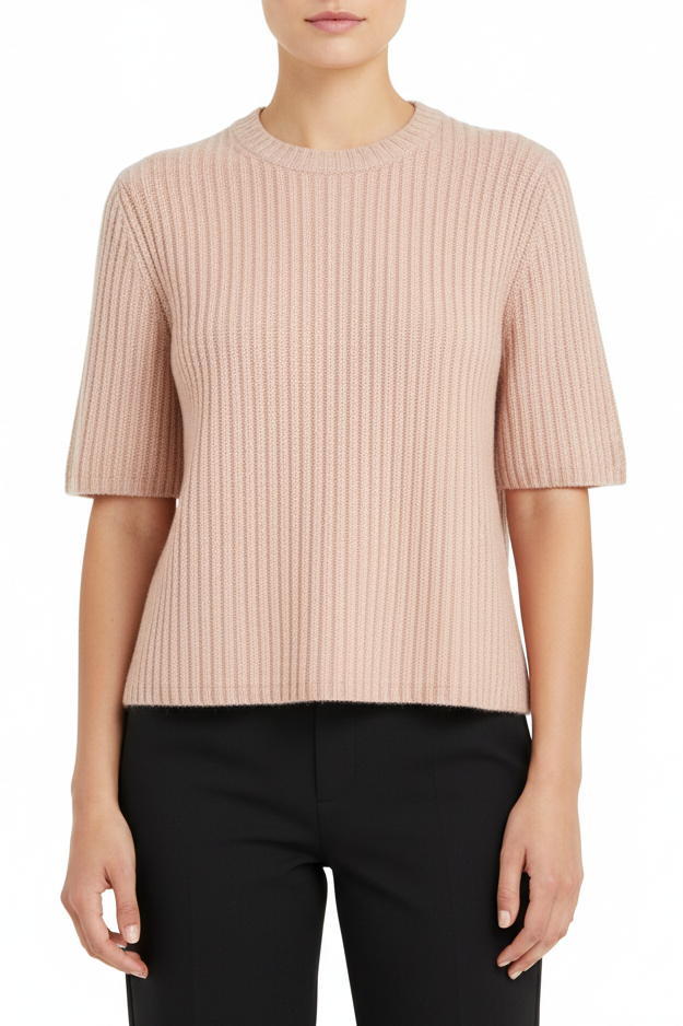 Person wearing a light pink ribbed sweater and black pants on a white background