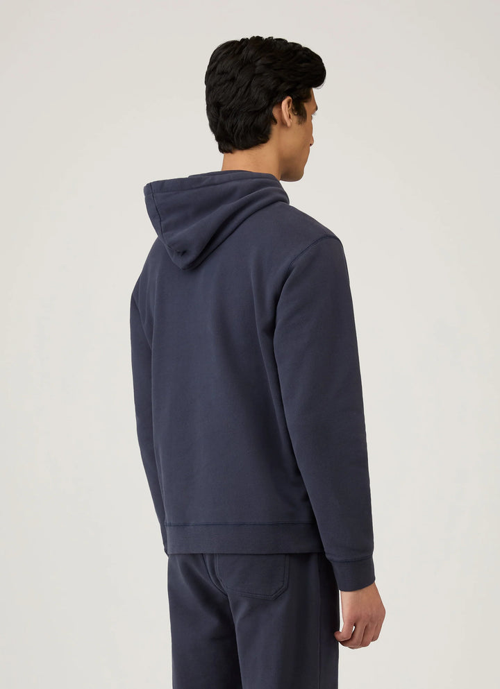 Person wearing a navy blue hoodie and pants on a light gray background