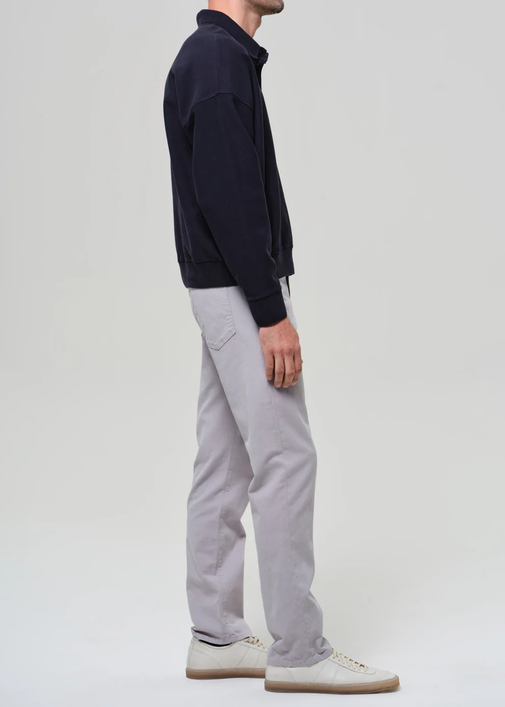 Person wearing a navy jacket and gray pants on a white background