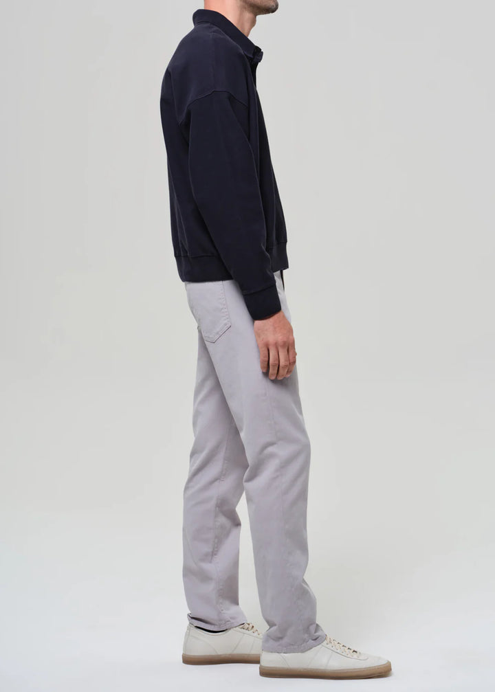 Person wearing a navy jacket and gray pants on a white background