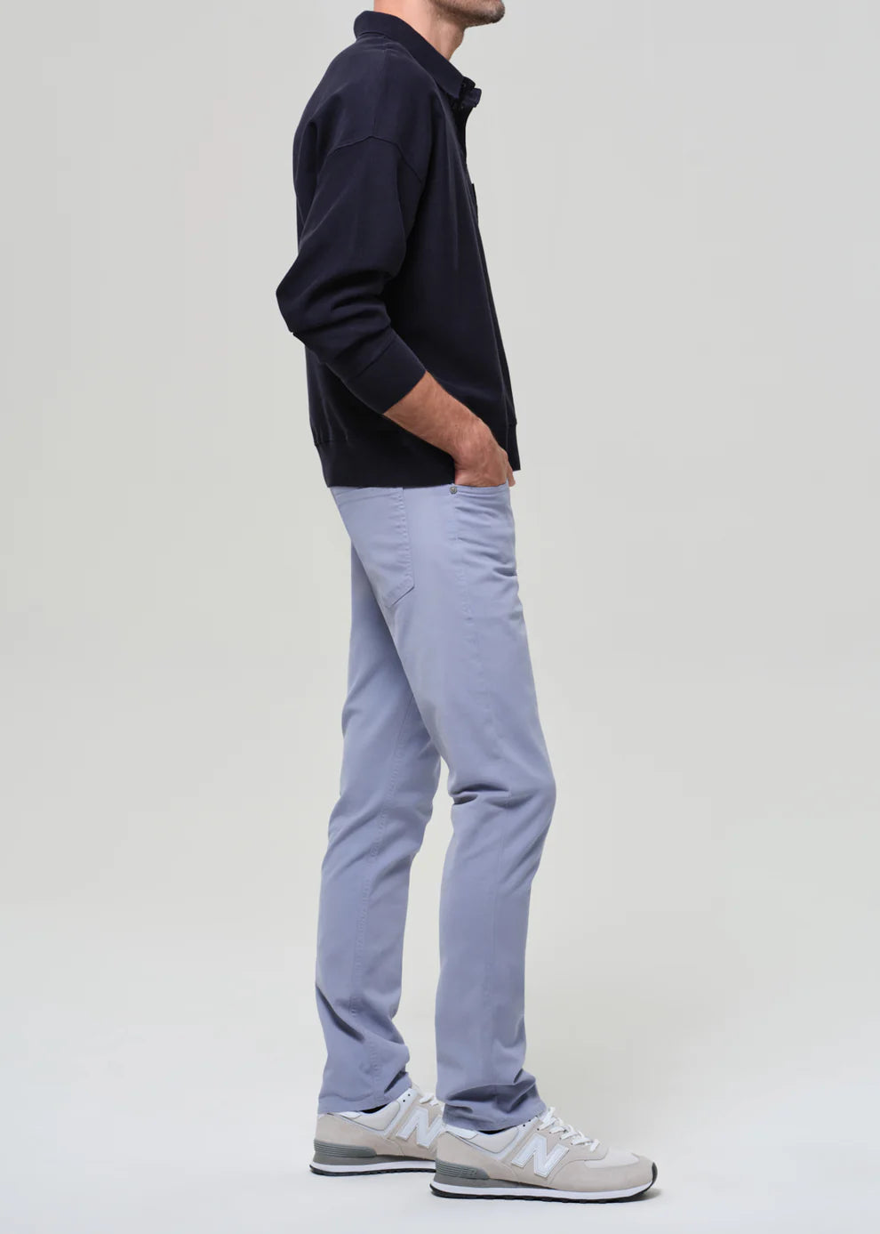 Person wearing a navy jacket and light gray pants on a white background