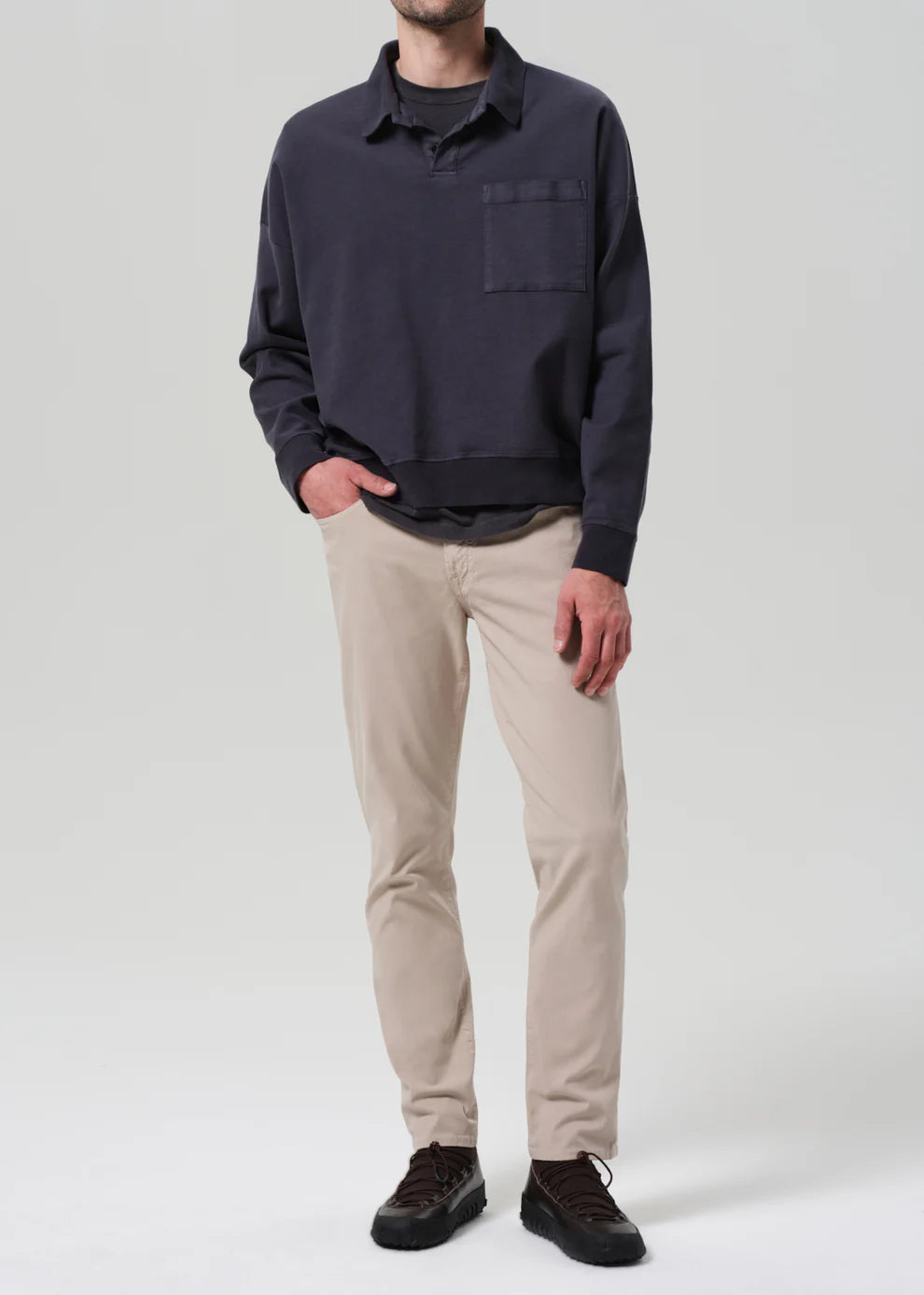 Person wearing a navy sweater and beige pants on a white background