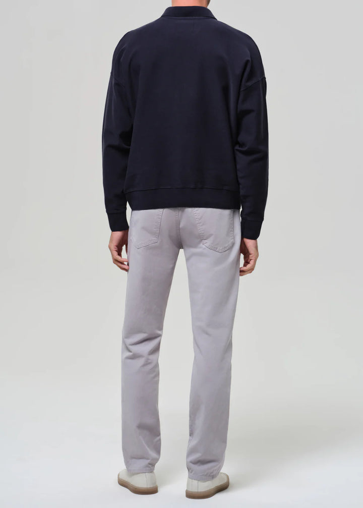 Person wearing a navy sweater and light gray pants on a white background