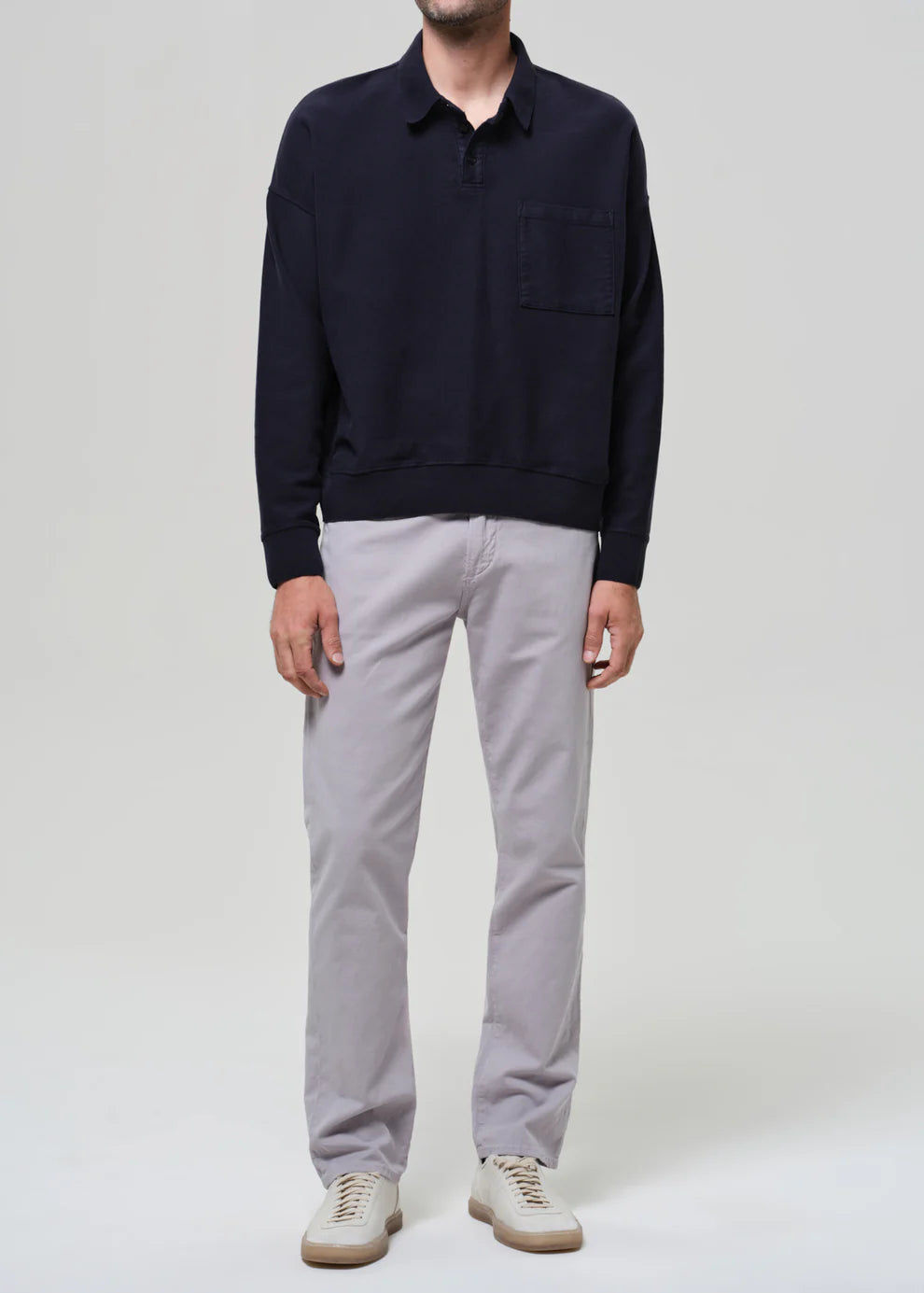 Person wearing a navy sweater and light gray pants on a white background