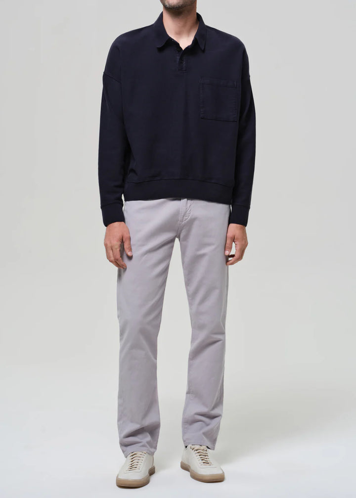 Person wearing a navy sweater and light gray pants on a white background