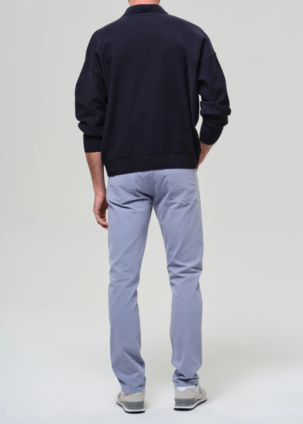 Person wearing a navy sweatshirt and light blue pants on a white background
