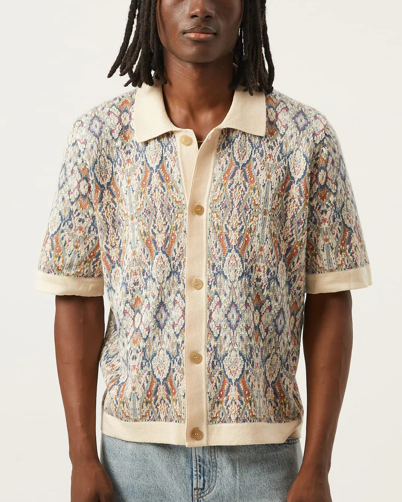 Person wearing a patterned short-sleeve shirt with a neutral background