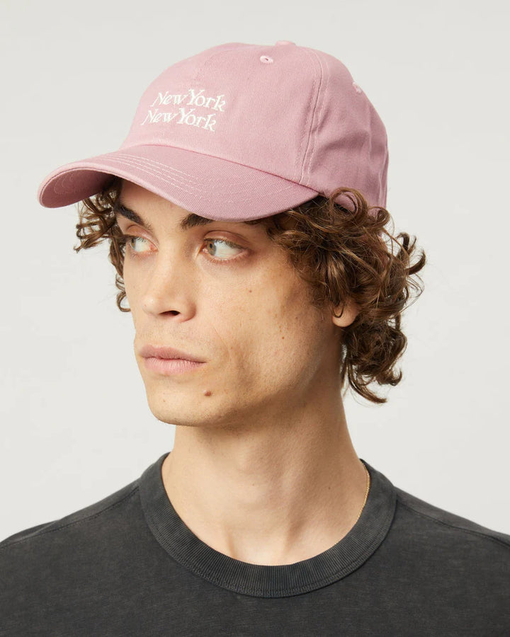 Person wearing a pink cap with 'New York' text on a plain background