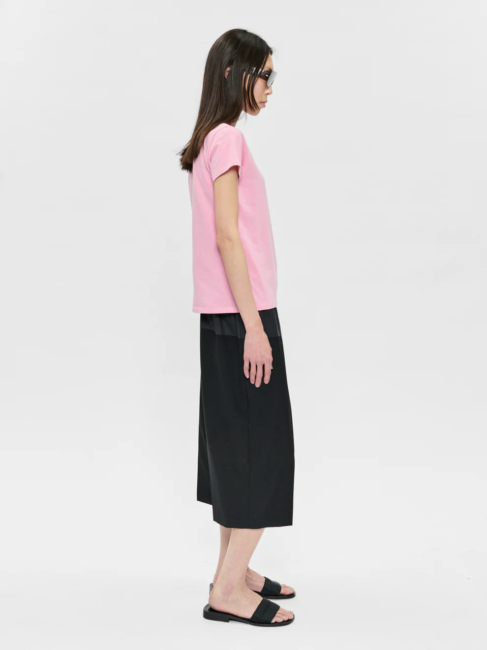 Person wearing a pink top and black skirt on a white background