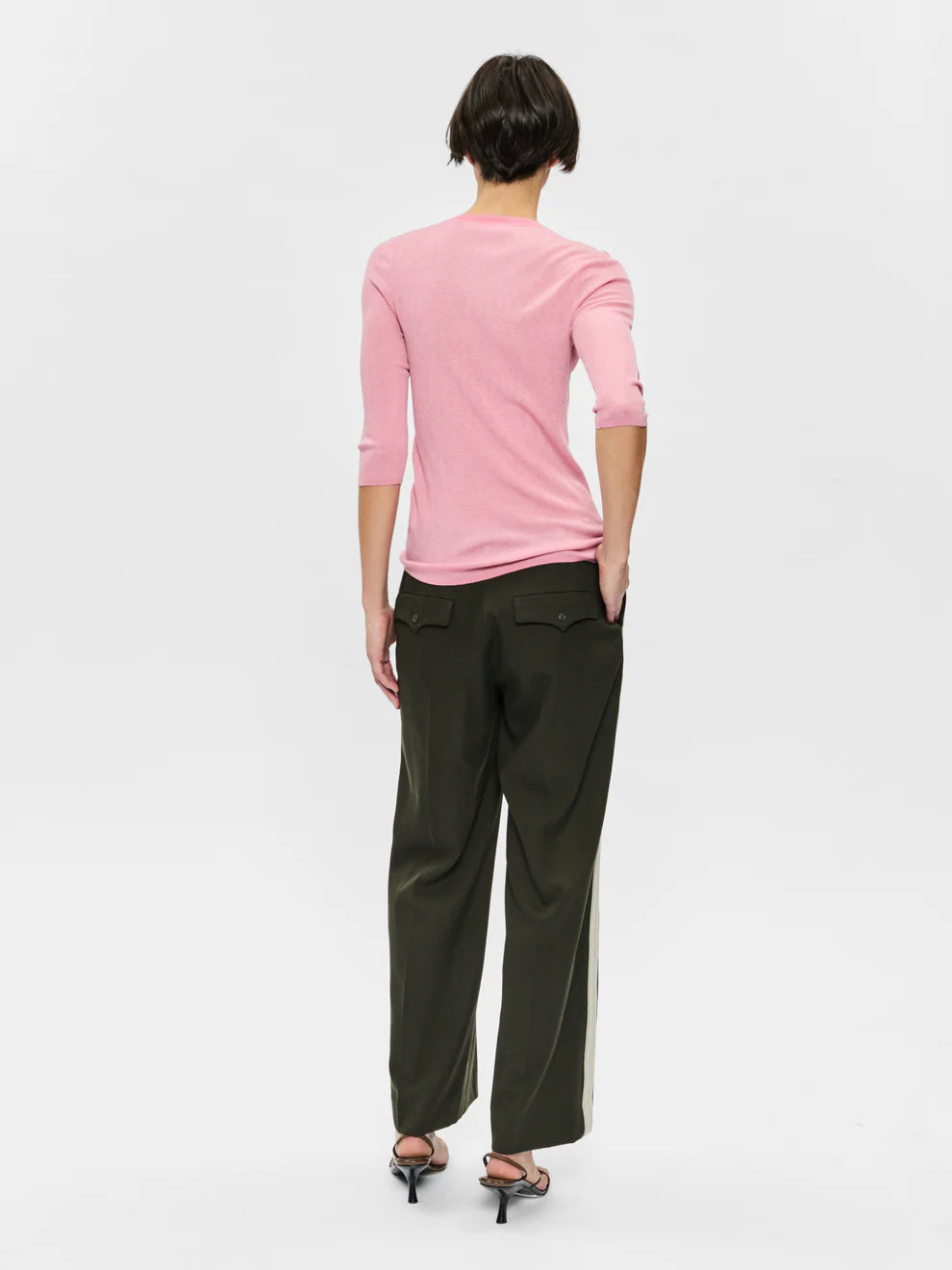 Person wearing a pink top and green pants on a white background