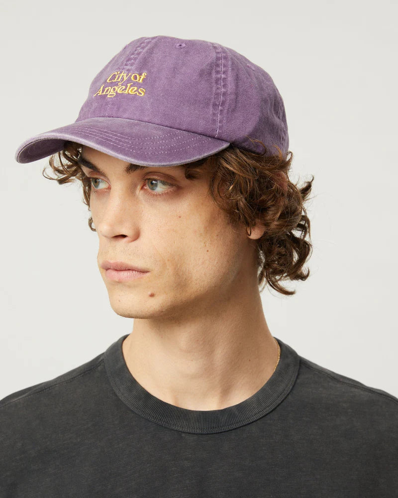 Person wearing a purple 'City of Angeles' cap on a plain background