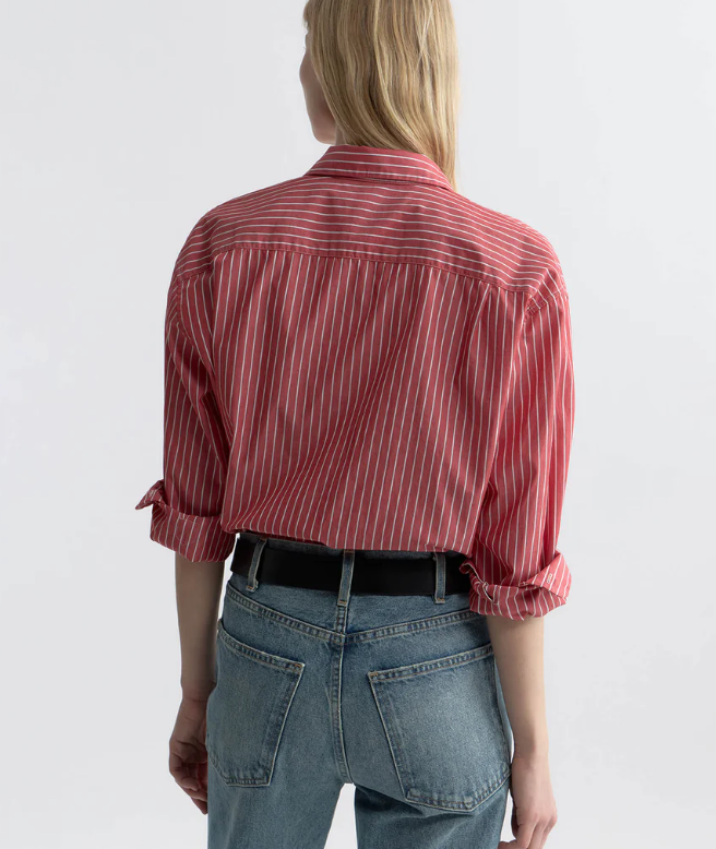 Person wearing a red and white striped shirt and blue jeans on a plain background