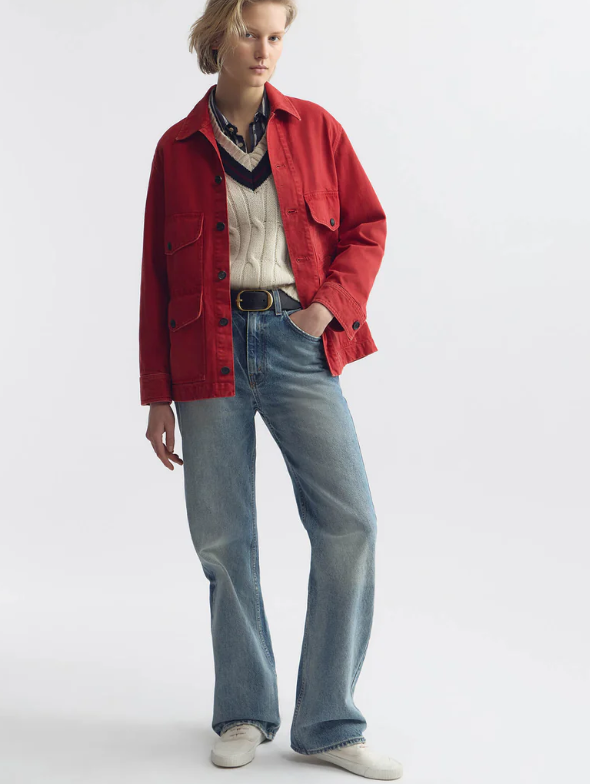 Person wearing a red jacket, white sweater, blue jeans, and white shoes on a white background