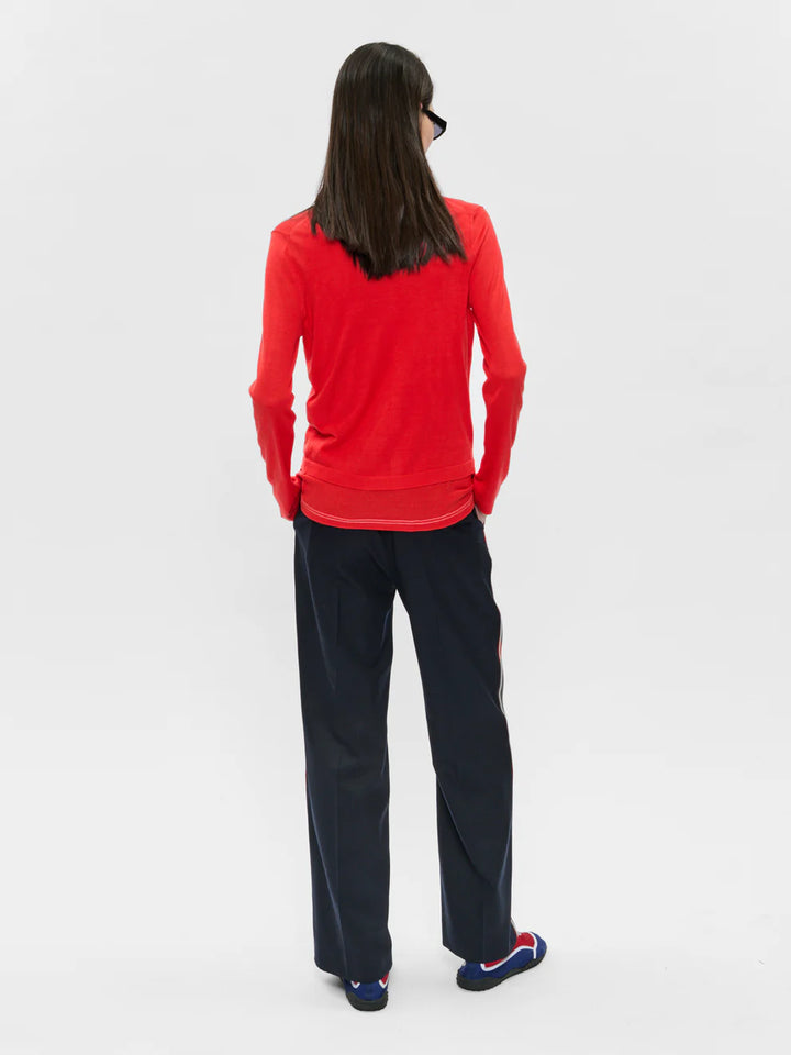 Person wearing a red long-sleeve shirt and black pants on a white background