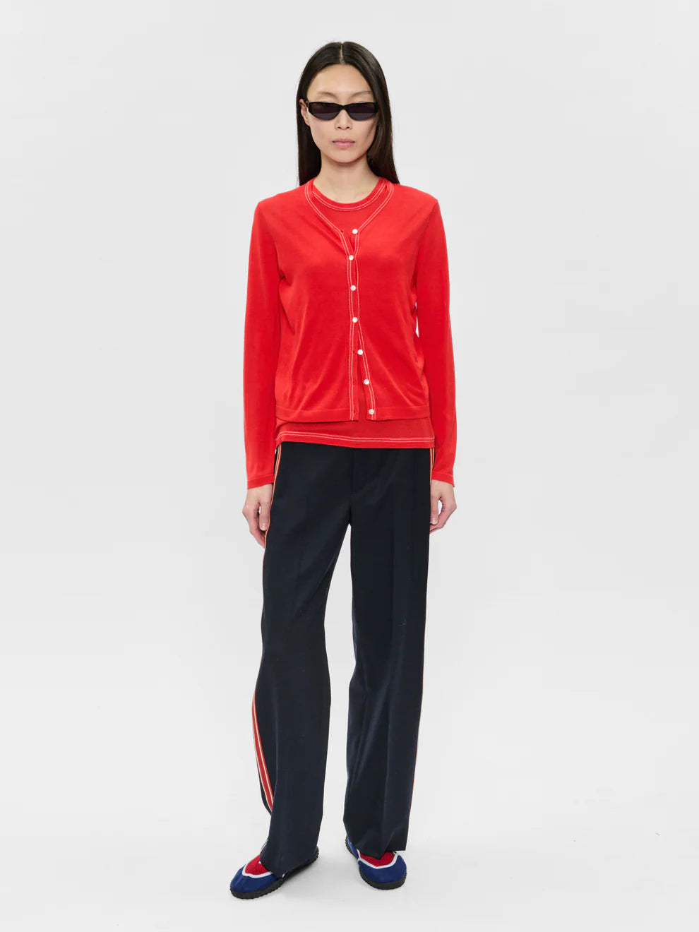 Person wearing a red top and black pants on a white background
