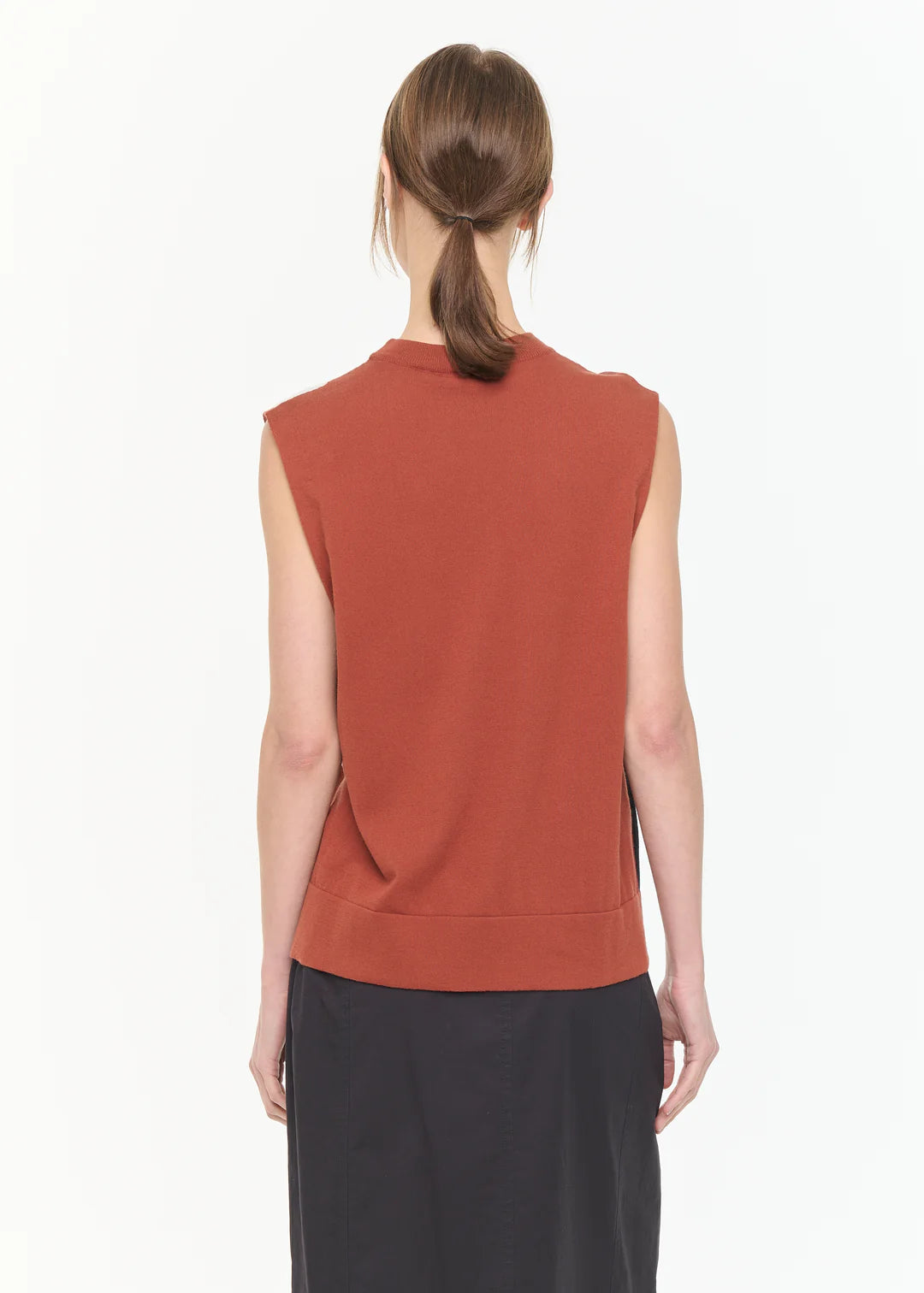 Person wearing a rust-colored sleeveless top on a white background