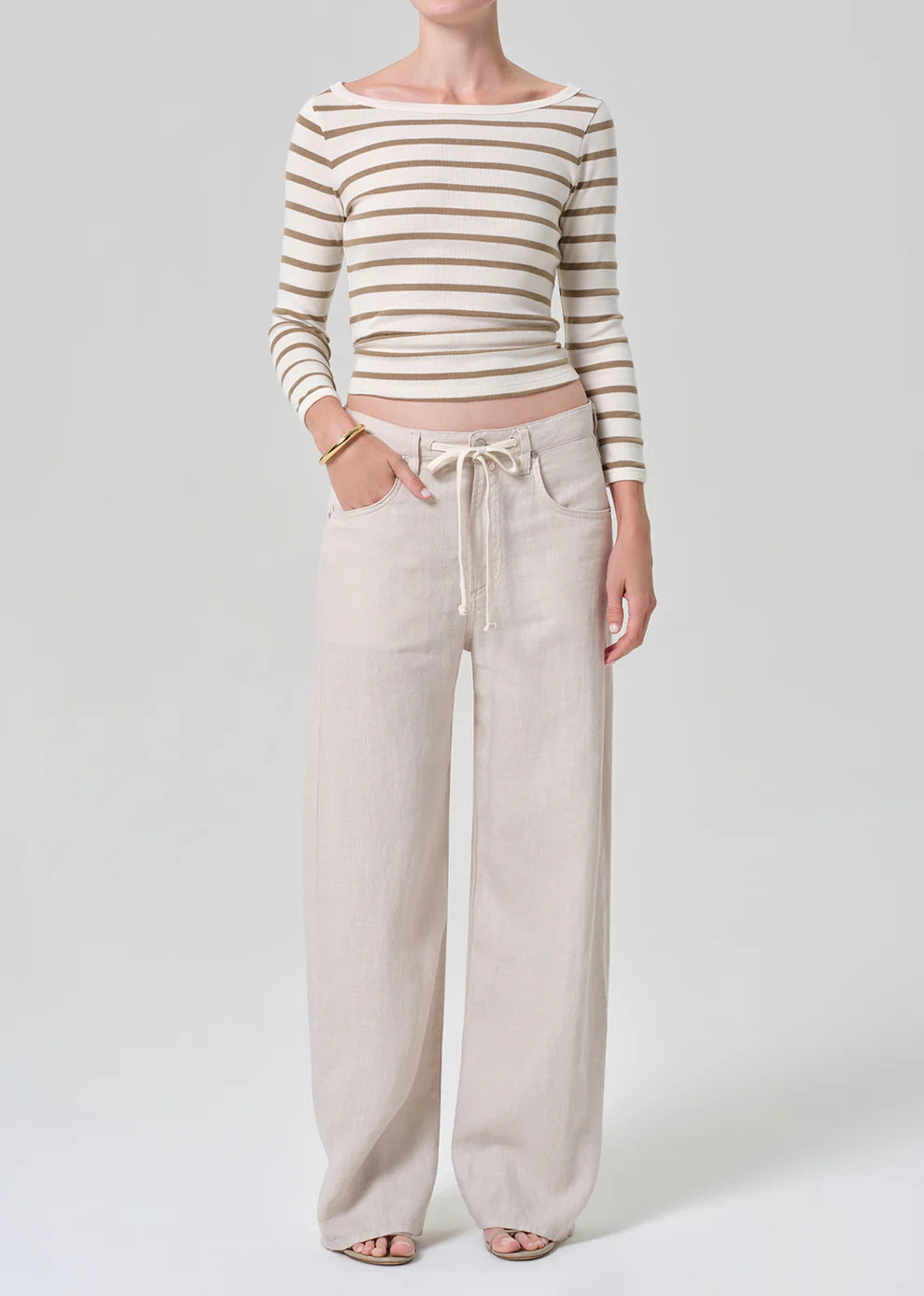 Person wearing a striped long-sleeve top and wide-leg pants on a white background