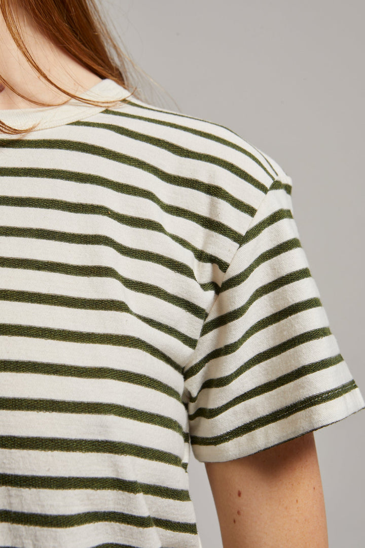 Person wearing a striped shirt with green and white horizontal stripes on a plain background