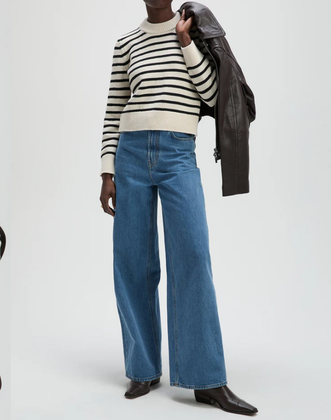 Person wearing a striped sweater and blue jeans on a white background