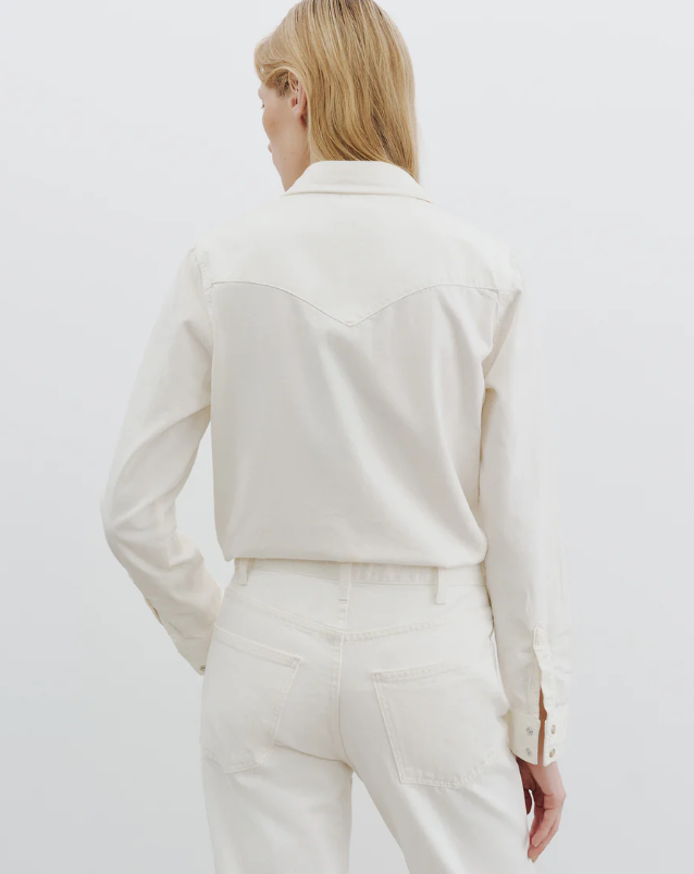 Person wearing a white blouse and pants against a plain background