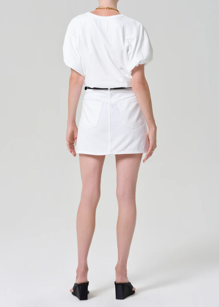 Person wearing a white outfit with a belt on a plain background