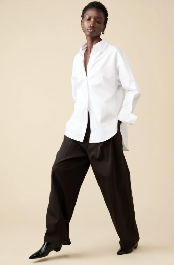 Person wearing a white shirt and black pants on a beige background