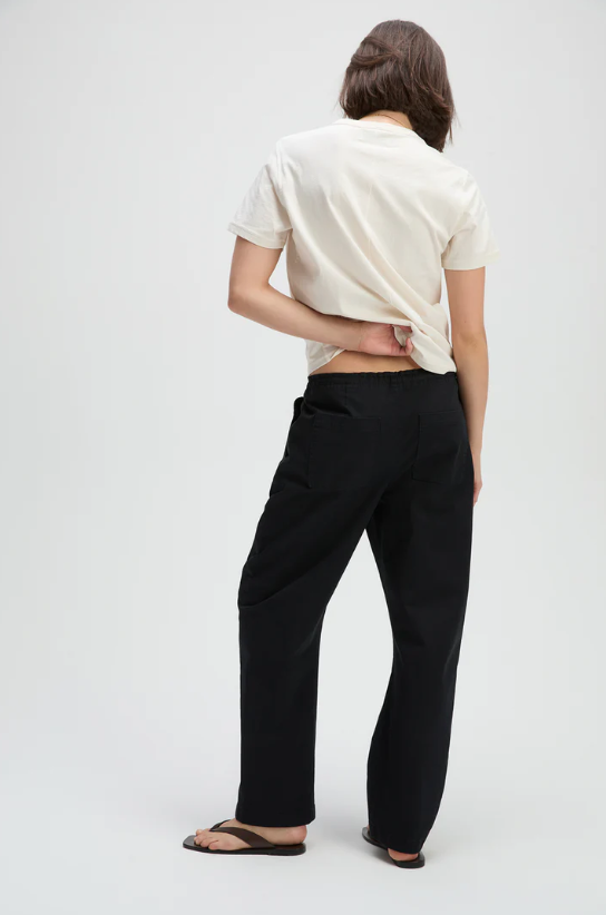 Person wearing a white shirt and black pants on a plain background
