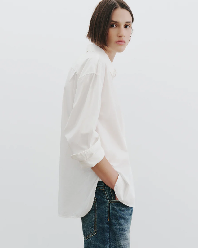 Person wearing a white shirt and blue jeans against a plain background