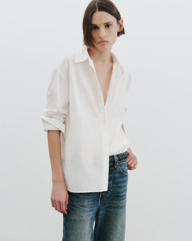 Person wearing a white shirt and blue jeans on a plain background