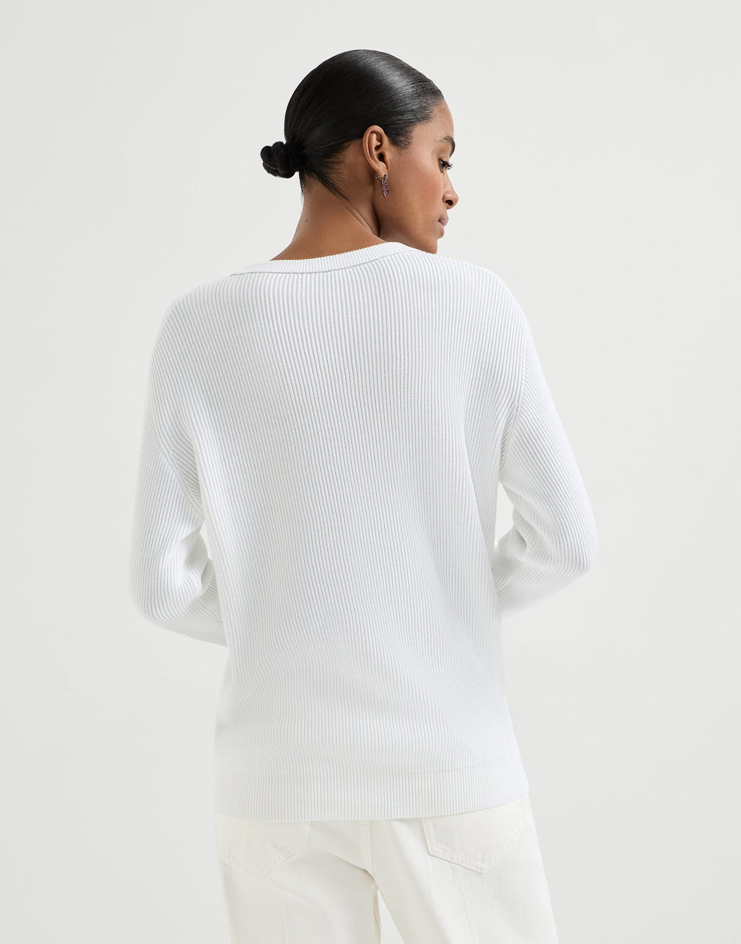 Person wearing a white sweater against a plain background