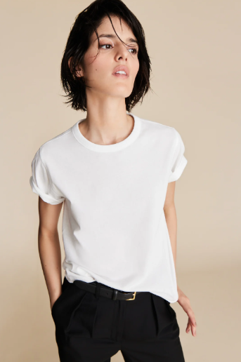 Person wearing a white t-shirt and black pants on a beige background