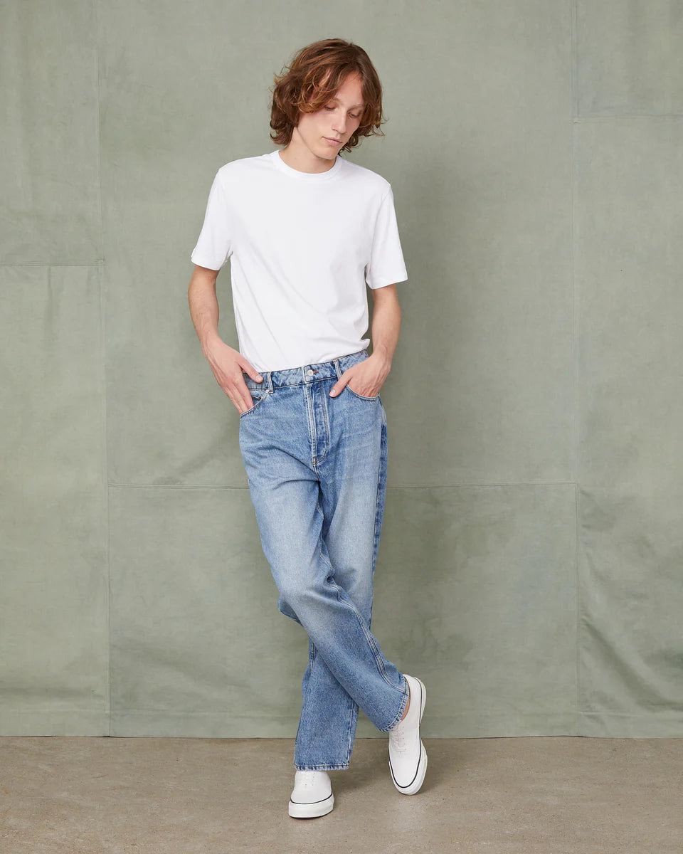 Person wearing a white t-shirt and blue jeans against a plain background