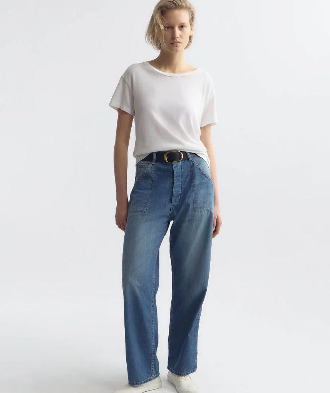 Person wearing a white t-shirt and blue jeans on a plain background