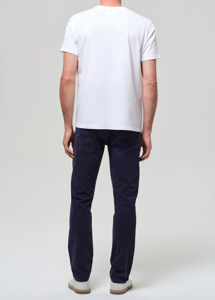 Person wearing a white t-shirt and dark pants on a plain background