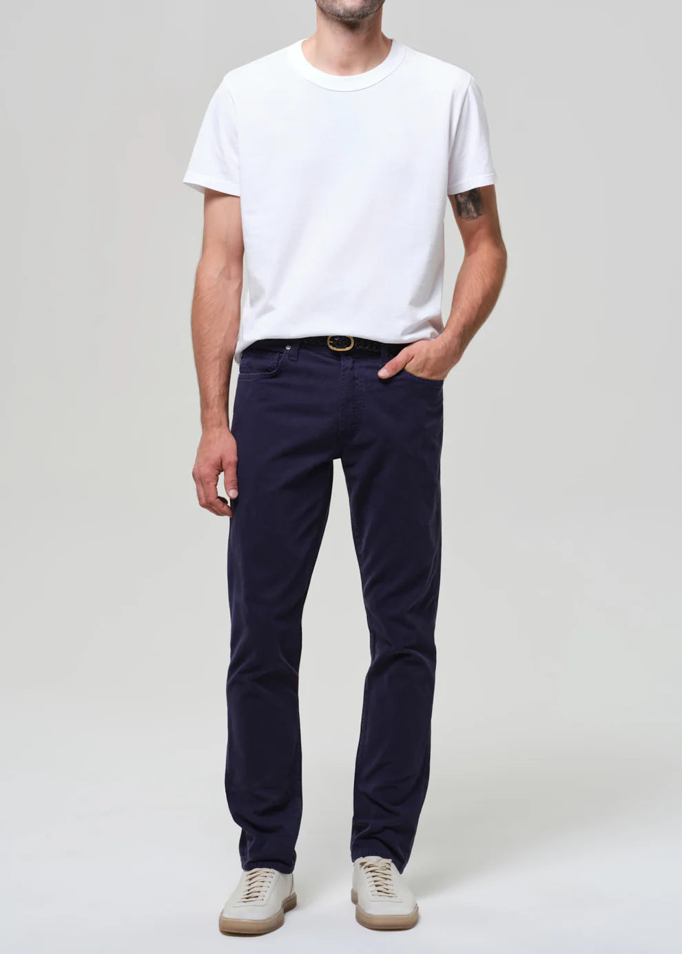 Person wearing a white t-shirt and navy pants on a plain background