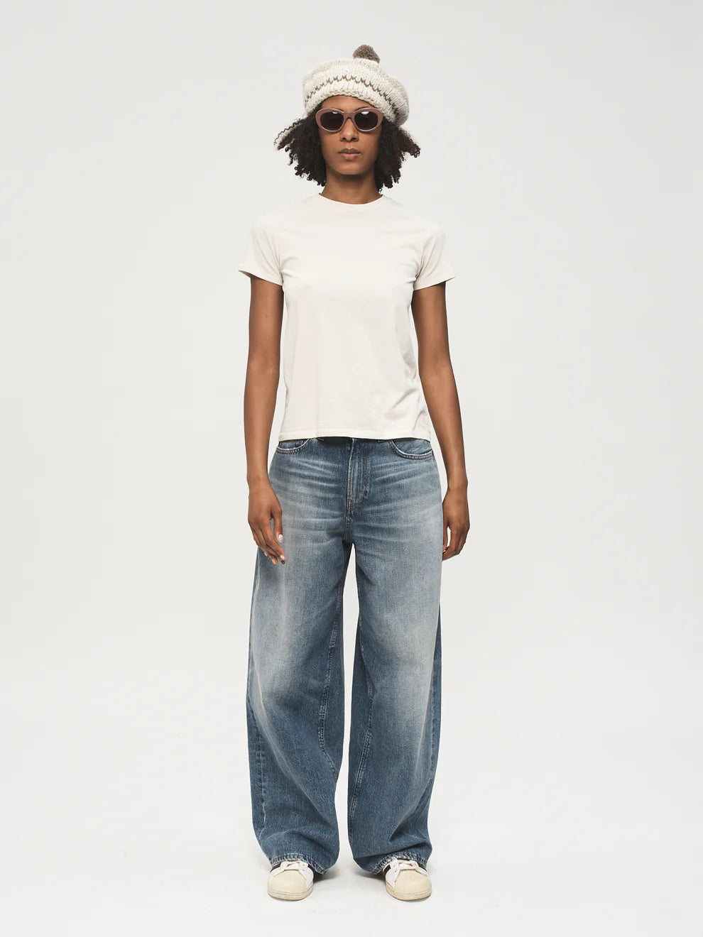 Person wearing a white t-shirt, blue jeans, and a beanie on a white background