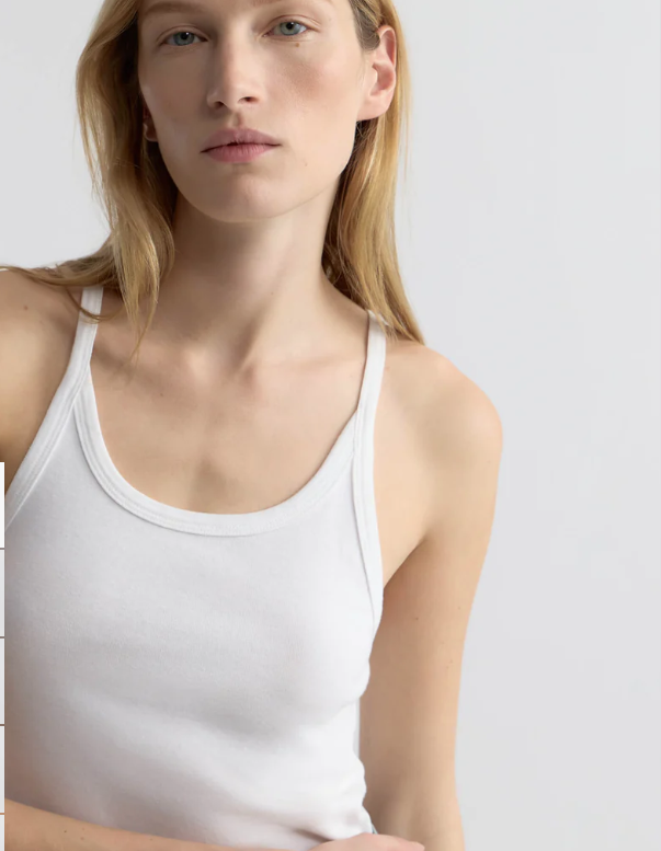 Person wearing a white tank top against a plain background