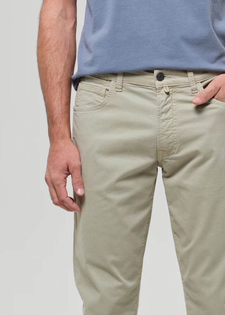 Person wearing beige pants and a blue shirt on a plain background