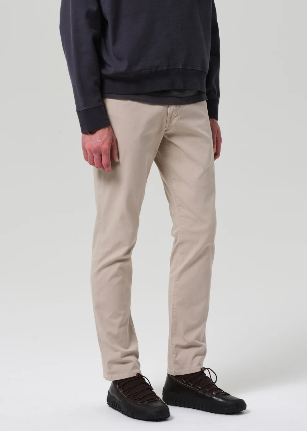 Person wearing beige pants and a dark sweater on a white background