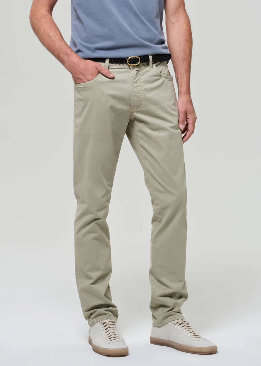 Person wearing beige pants and a light blue shirt on a white background